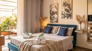 Un dormitori amb llit, taula de nit, làmpada, televisió i finestra amb cortines.
