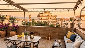 Una terrassa al terrat amb una taula, cadires, un sofà i vista a la ciutat.
