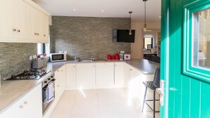 Una cucina moderna con una grande isola, una TV a schermo piatto e una porta color petrolio.