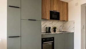 Une cuisine moderne avec des meubles gris, un élément supérieur en bois, un four encastré et un pare-feu en marbre.