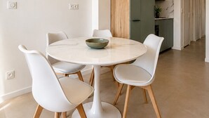 Un espace repas moderne avec une table ronde, des chaises blanches et un saladier posé sur la table.