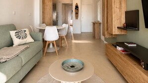 Un salon moderne comprenant un canapé, une table basse, un coin repas et un téléviseur fixé à un mur en bois.