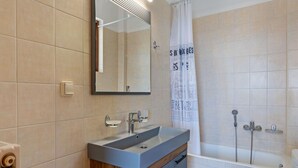 Un bagno con lavandino, specchio, doccia e WC.