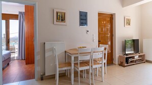 Una stanza con un tavolo da pranzo, sedie, una televisione e una porta che dà su un balcone.