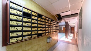 A hallway with a wall of numbered storage boxes, a tiled floor, and a door at the end. - (MDP80314) 1 bedroom apartment in the center of Madrid (Madrid)