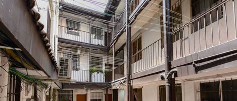 Een meerlaags gebouw met balkons, een binnentuin en zichtbare leidingen.