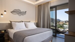 Ein modernes Hotelzimmer mit einem großen Bett, Blick auf die Stadt und einem Balkon mit Tisch und Stühlen.