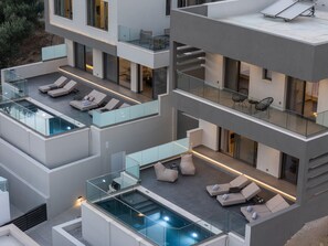 A multi-level modern building with glass balconies, outdoor seating areas, and a rooftop pool. - Maple Villa 2 Superior Sea View Villa, Walking Distance From Plakias Beach (Agios Vasileios)