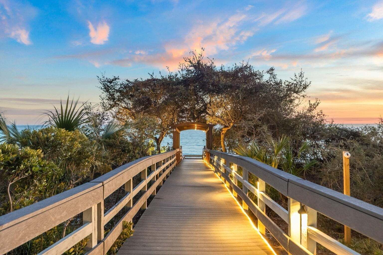 A wooden boardwalk leading to a covered area with a view of the sea.