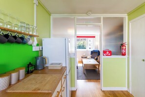 A compact kitchen with a refrigerator, coffee maker, and a window with a view. - Serene 2BDR Retreat by Holyrood Park (Edinburgh)