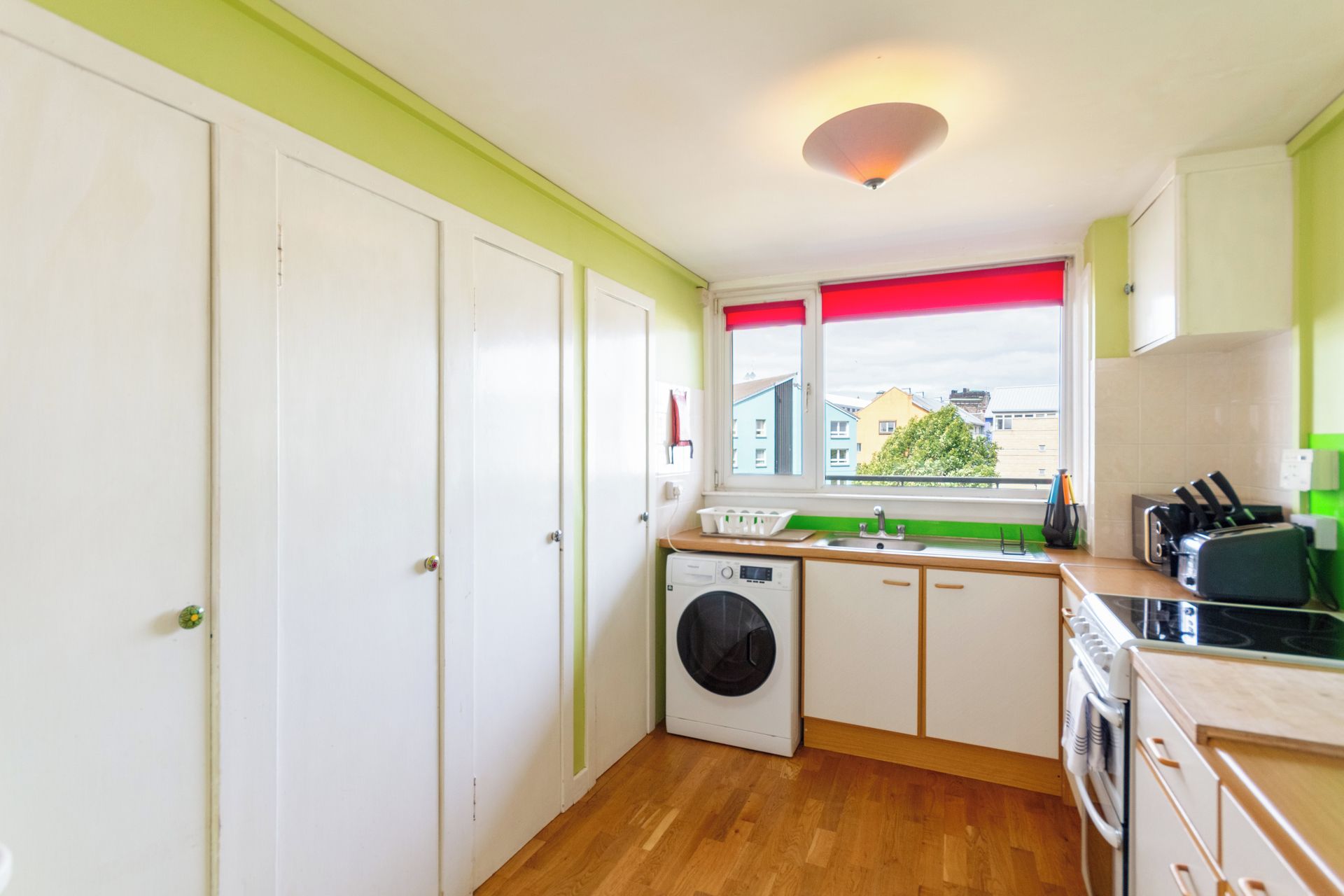 A compact kitchen with a washing machine, a sink, and a stove.