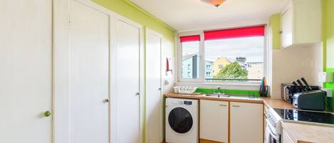 A compact kitchen with a washing machine, a sink, and a stove.
