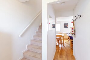 A staircase leading to a room with a wooden floor, a dining area with chairs and a table, and a wall with a poster. - Serene 2BDR Retreat by Holyrood Park (Edinburgh)