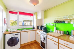 A compact kitchen with a washing machine, a stove, and a sink. - Serene 2BDR Retreat by Holyrood Park (Edinburgh)