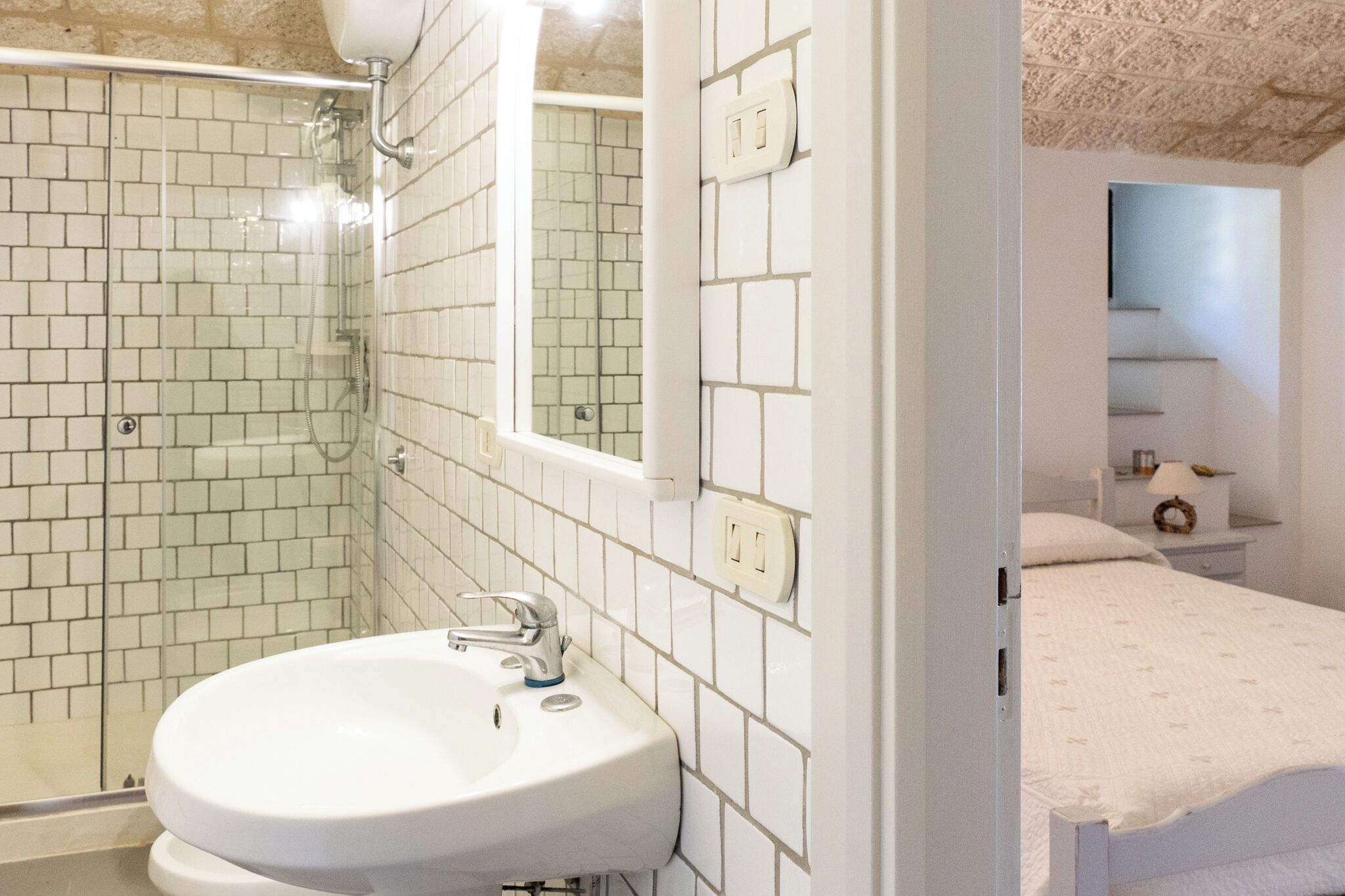 A bathroom with a white sink, a glass shower enclosure, and a mirror.