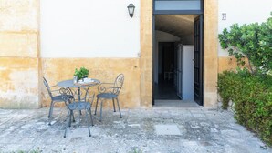 Ein Innenhof mit Tisch und Stühlen, einem Blumentopf und einer Tür zu einem Innenbereich.