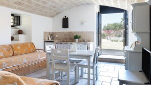 Ein Wohnzimmer mit Sofa, Esstisch, Stühlen und einem Fernseher.
