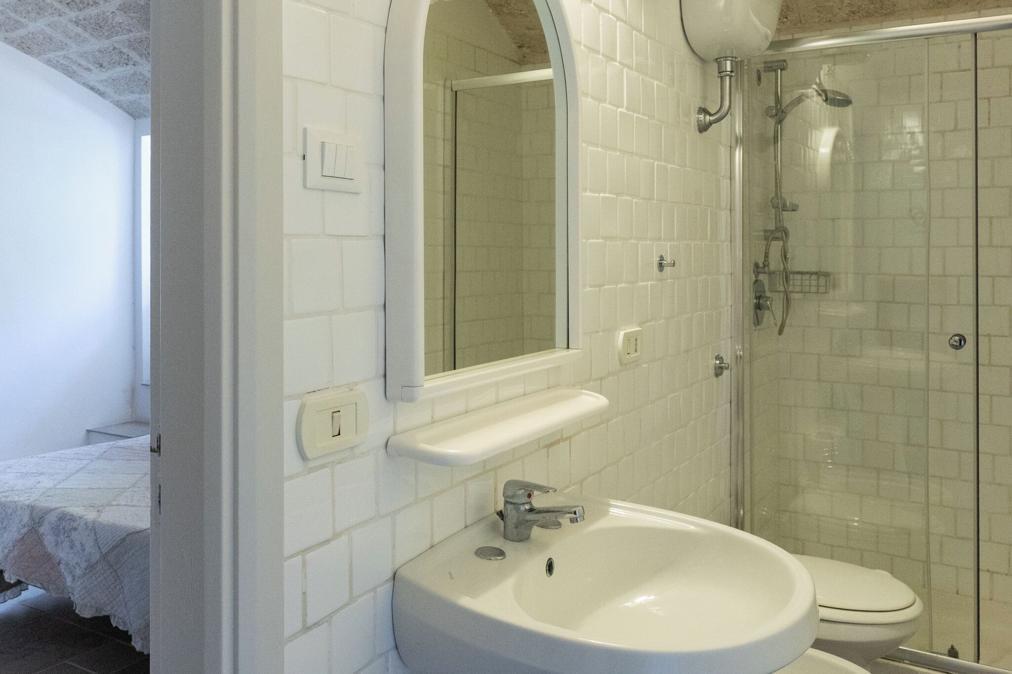 A bathroom with a white sink, mirror, and shower.