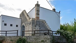 A building with a stone staircase leading to a white door, a metal railing, and a clear sky.