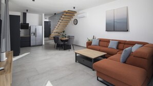 Ein stilvoller Wohnraum mit Treppe, Essbereich, Sofa und Küche.