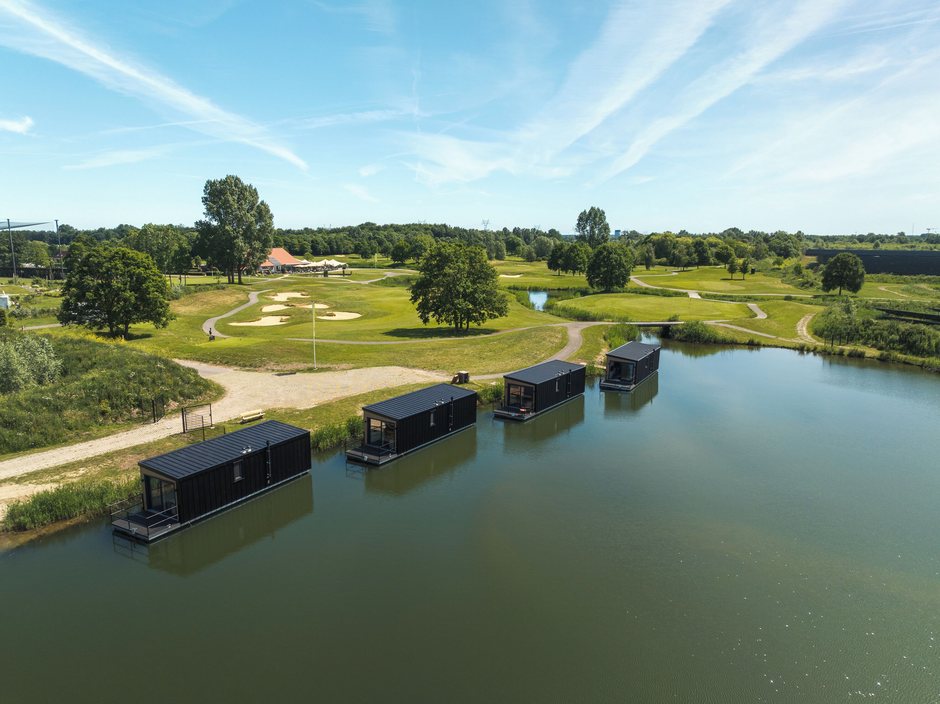 A lakeside property with floating structures, a golf course, and a small bridge.