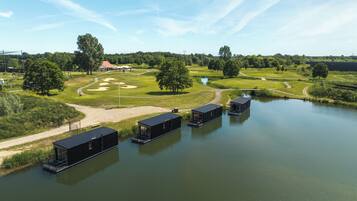 A lakeside property with floating structures, a golf course, and a small bridge.