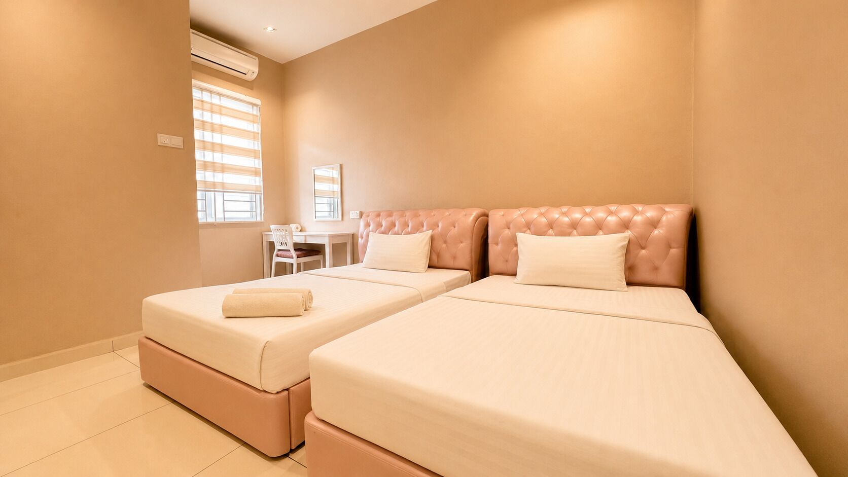 A hotel room with two beds, a desk, and a chair.