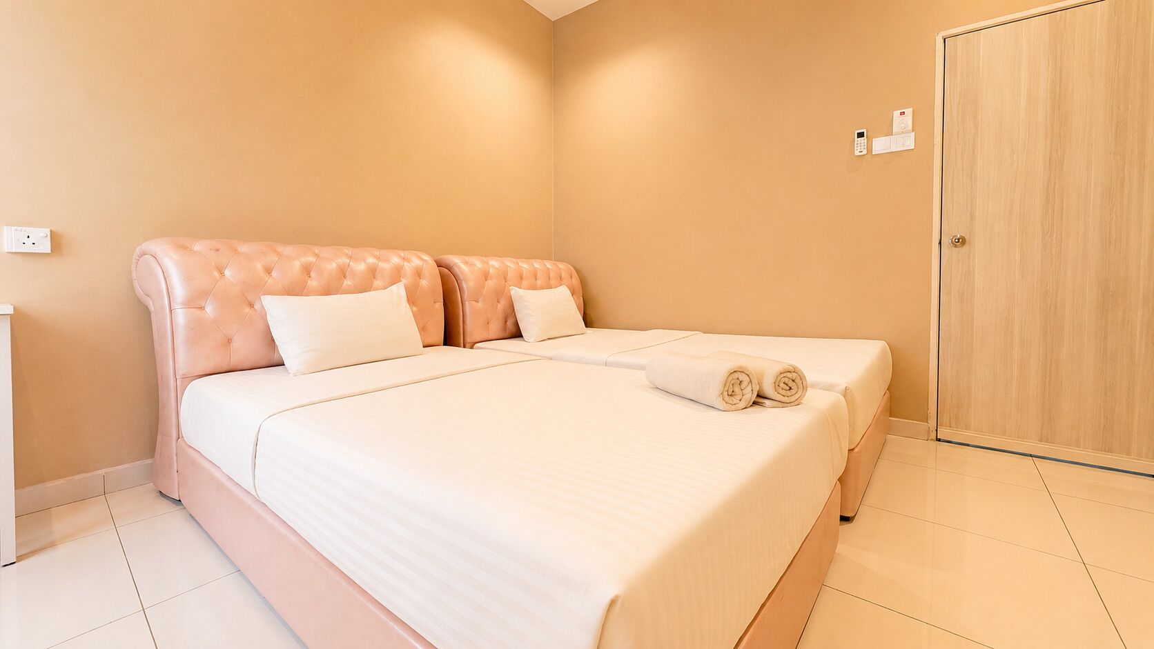 Ein Schlafzimmer mit einem Bett, zwei Kissen, einem Nachttisch und einer Holztür.