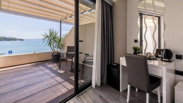 Een balkon met uitzicht op zee, een bureau met stoel en een bloempot.