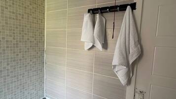 A bathroom with a bathtub, tiled walls, and a towel rack with towels.