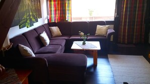 Una sala de estar con un sofá morado, una mesita con un florero y una escalera.