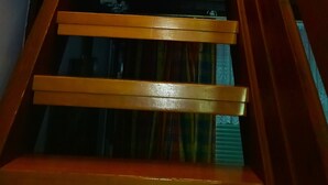 Una escalera de madera con barandilla que lleva a una habitación con ventana y cortina.