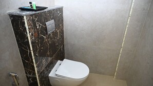 A bathroom with a toilet, a marble vanity, and a shower. - HOTEL SIYAGRAND (Tirupati)