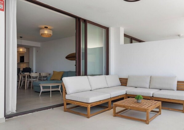 A modern living room with a sectional sofa, a wooden coffee table, and a dining area in the background. - Casa de Daisy | Sea View - Pool - Balcony (Fuengirola)