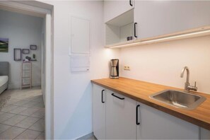 A modern kitchen with a wooden countertop, stainless steel sink, and white cabinets. - C14 - Seewirt Apartments: 1-Bedroom Apartment with Shower (St. Kanzian am Klopeiner See)