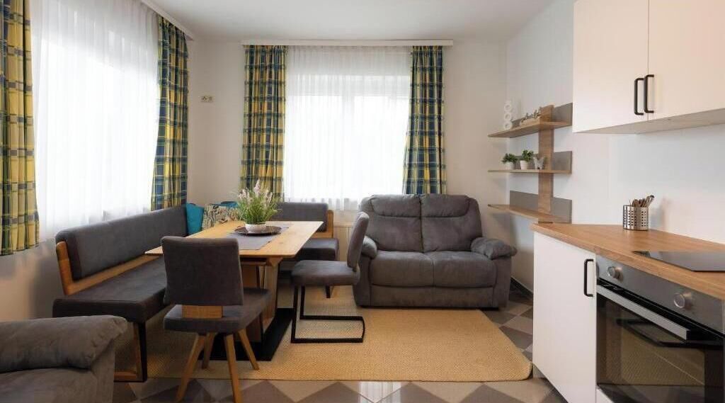 A modern living room with a sofa, a dining table, and a kitchen area with a stove.