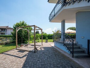 Une terrasse avec une balançoire, un escalier et un bâtiment doté d’un balcon.