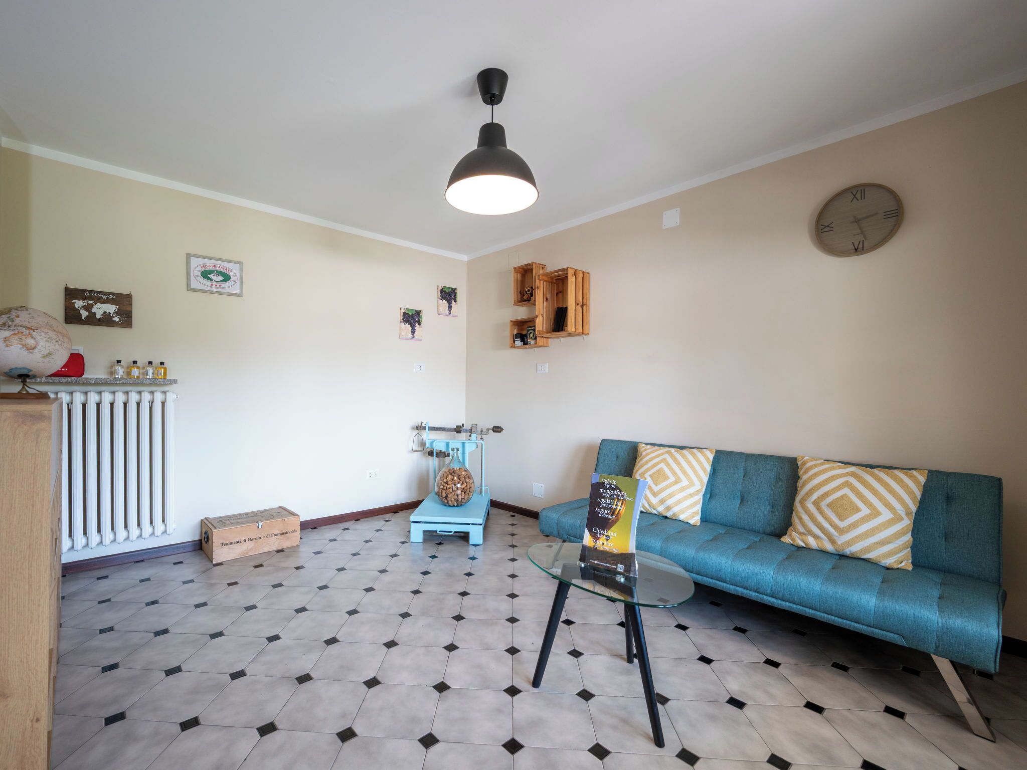 Un salon avec un canapé bleu, une table basse en verre, un globe terrestre et une horloge au mur.
