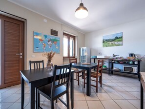 Un coin repas avec une table et des chaises en bois, une carte du monde accrochée au mur, un réfrigérateur et un plan de travail de cuisine avec divers objets.
