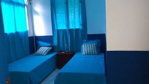 Ein Zimmer mit zwei Einzelbetten, jeweils mit blauer Bettdecke und passenden Kissen.