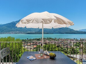 Varanda com mesa, guarda-sol, uma garrafa, um copo e uma tigela de uvas.