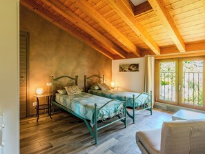 Quarto com duas camas, teto de madeira, um quadro na parede e janela com vista.