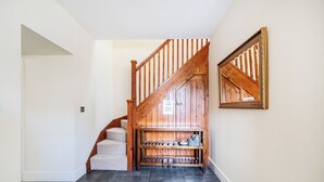 A staircase with wooden railings and a small shelf with dishes. - The Dairy (Corwen)