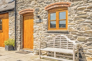 Un edificio de piedra con una puerta de madera, una ventana y un banco.