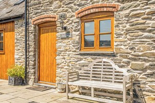A stone building with a wooden door, a window, and a bench.