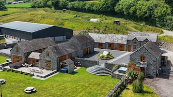 A stone building with a circular driveway, a large barn, and a grassy area with picnic tables.