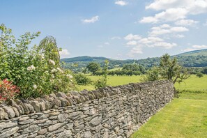 Un mur de pierre offrant une vue sur des collines ondoyantes et un ciel dégagé.