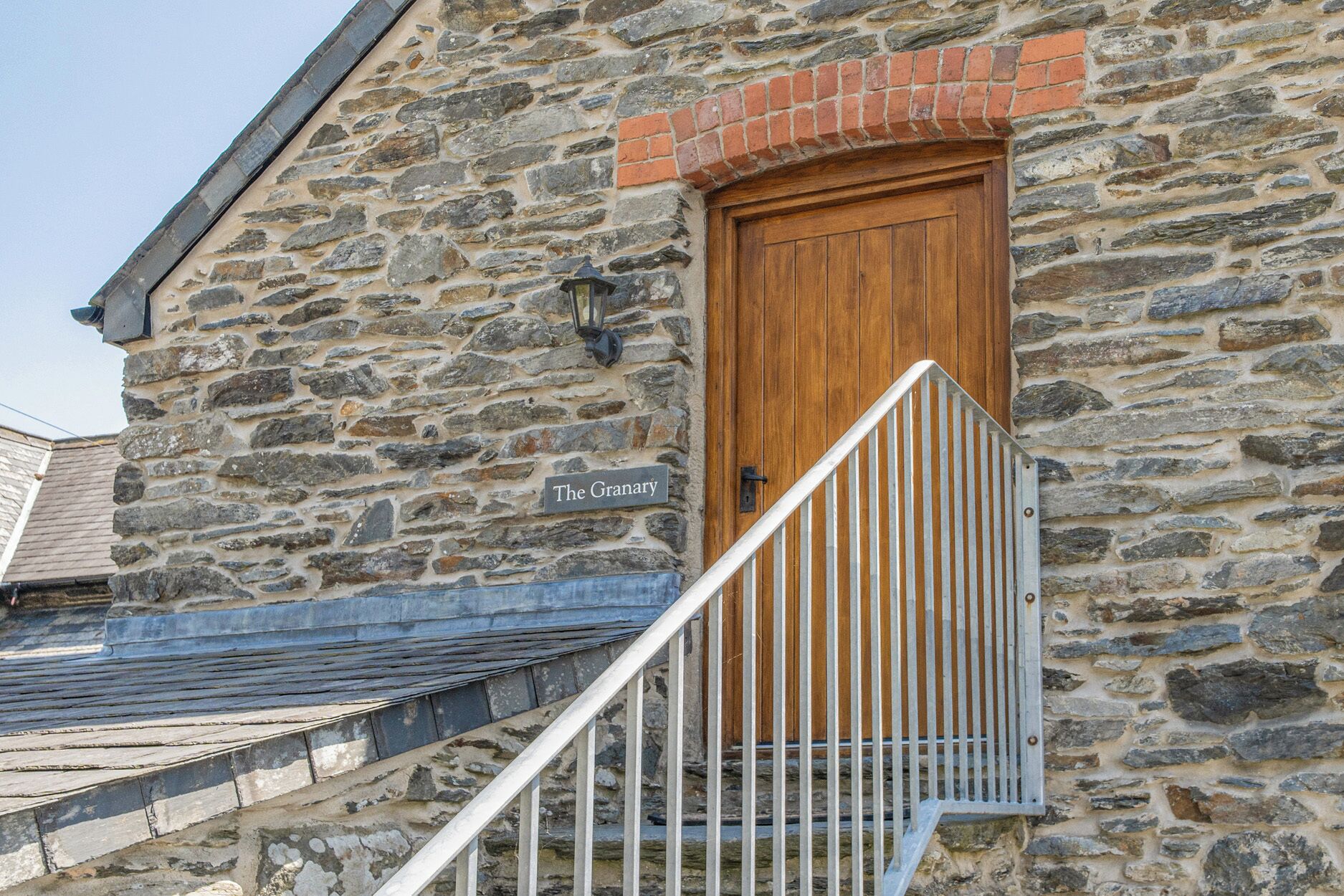 Edifici de pedra amb una porta de fusta, un rètol que diu 'The Granary' i una escala metàl·lica que condueix a l'entrada.