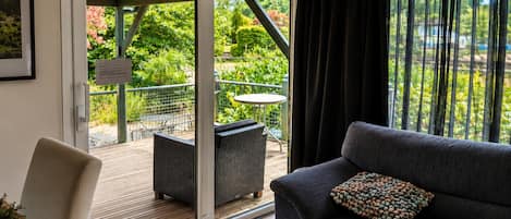A room with a sofa, a dining table, and a sliding glass door leading to an outdoor area with a patio table and chairs.