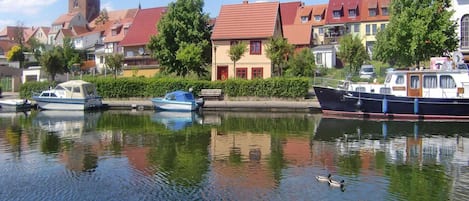 A calm waterway with boats, a duck, and buildings with red roofs.
